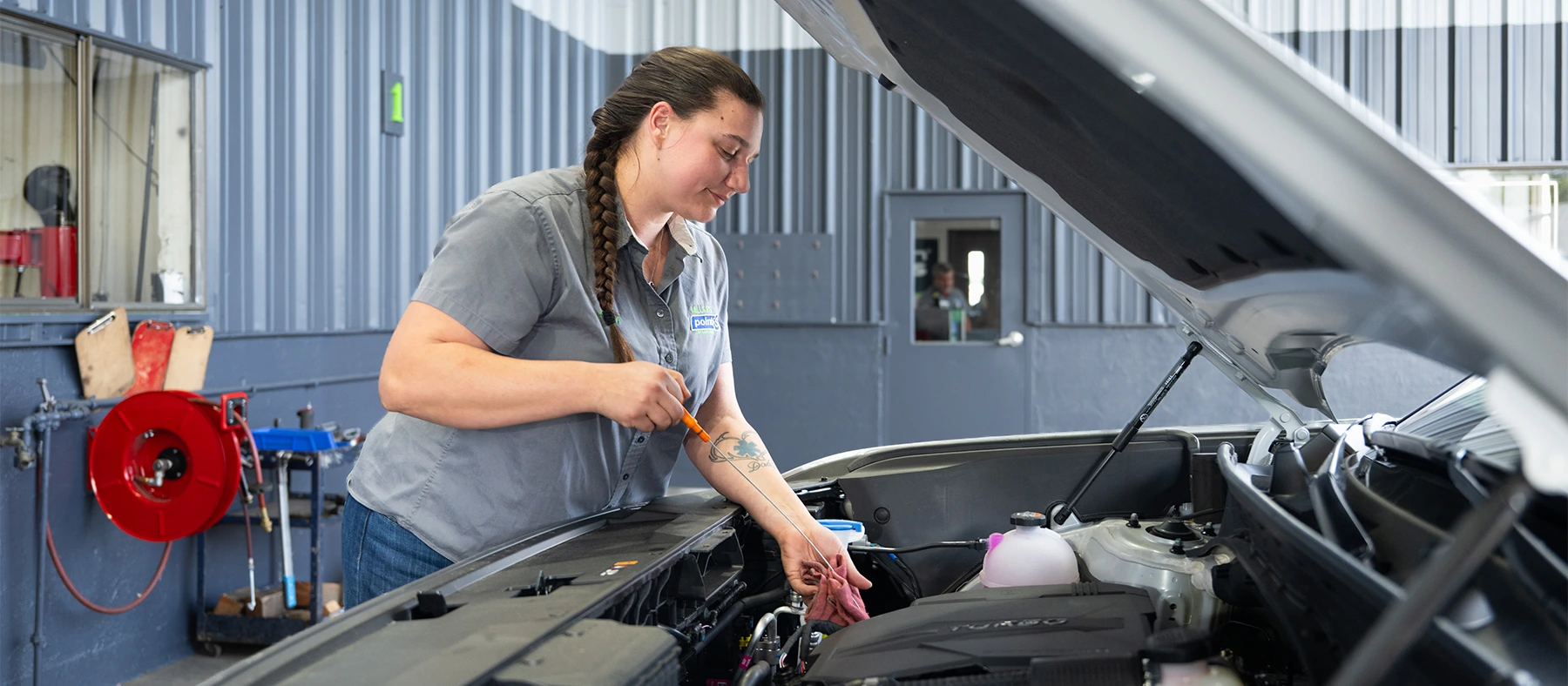 A Point S technician checking a vehicle's oil level with the dipstick