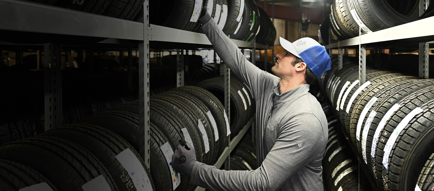 Point S technician organizing tires on warehouse shelves